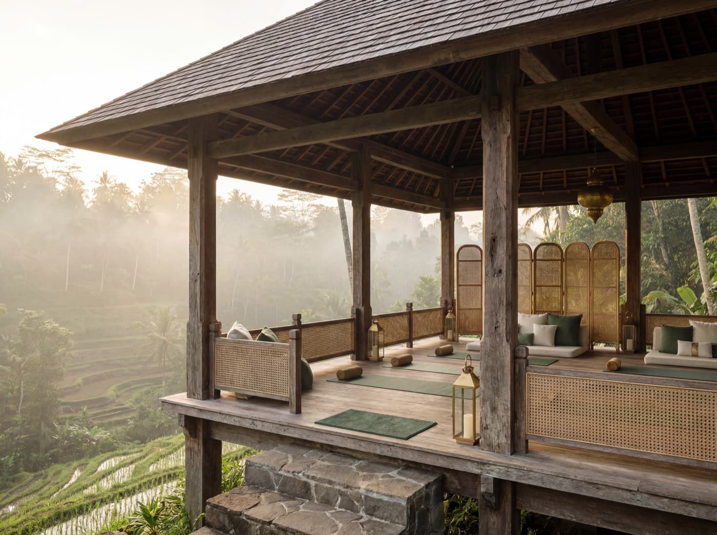 Open-air ironwood yoga shala on a timber podium with a vaulted shingle roof, overlooking the misty Ubud rice terraces